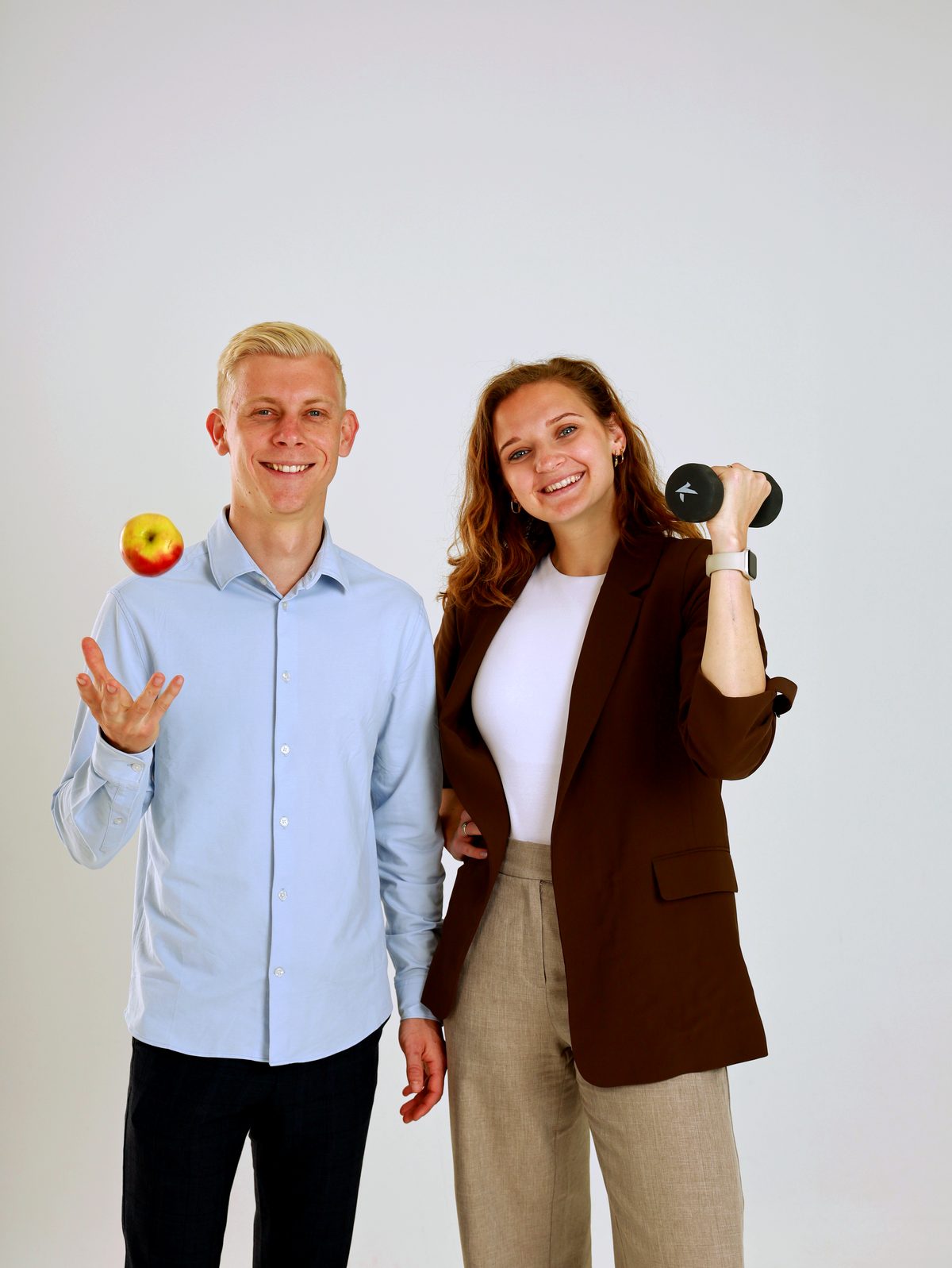 Twee VitsAll-medewerkers, lachend met een appel en een dumbbell